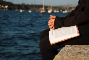 person praying solely while opening a prayer book